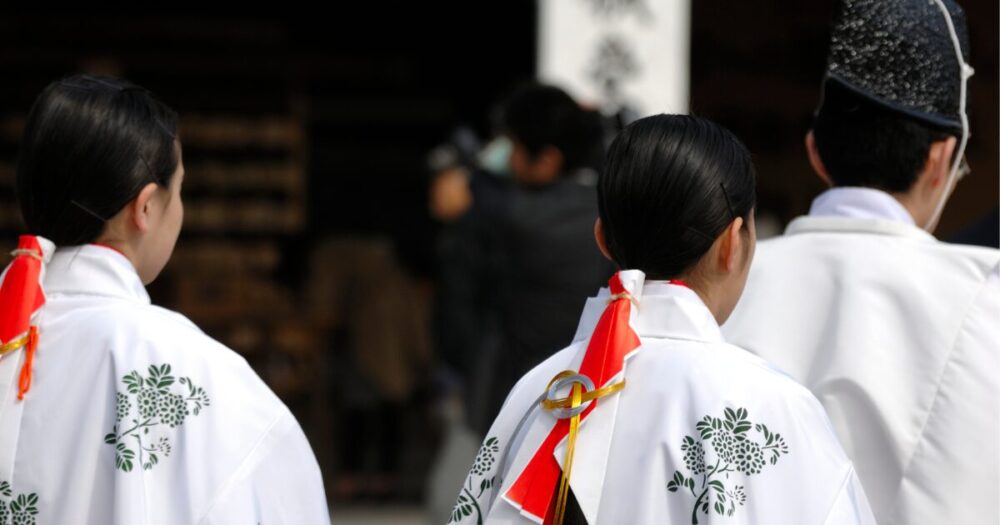 A priest and a shrine maiden dressed in sacred robes for a Shinto ceremony